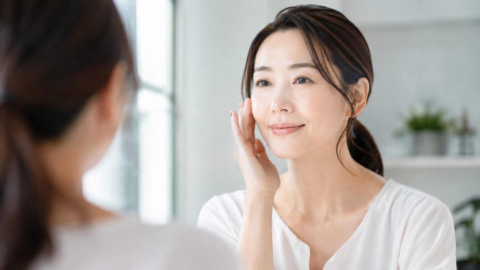 鏡を見ながら肌の状態を確認する40代の日本人女性