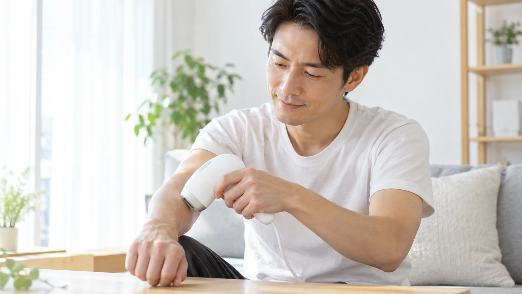 自宅で家庭用光美容器を使って腕のムダ毛ケアをする男性